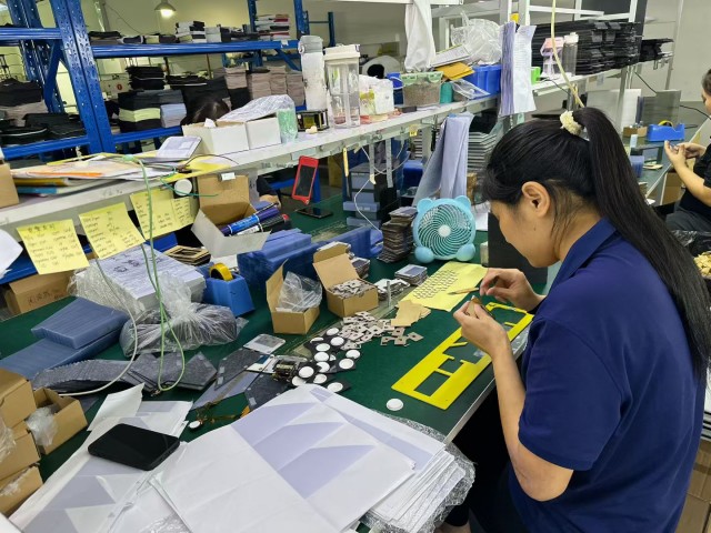 Close-up of a worker assembling mobile phone case parts at a manufacturing workstation, showcasing Fita's reliable sourcing partnership and supply chain quality control.